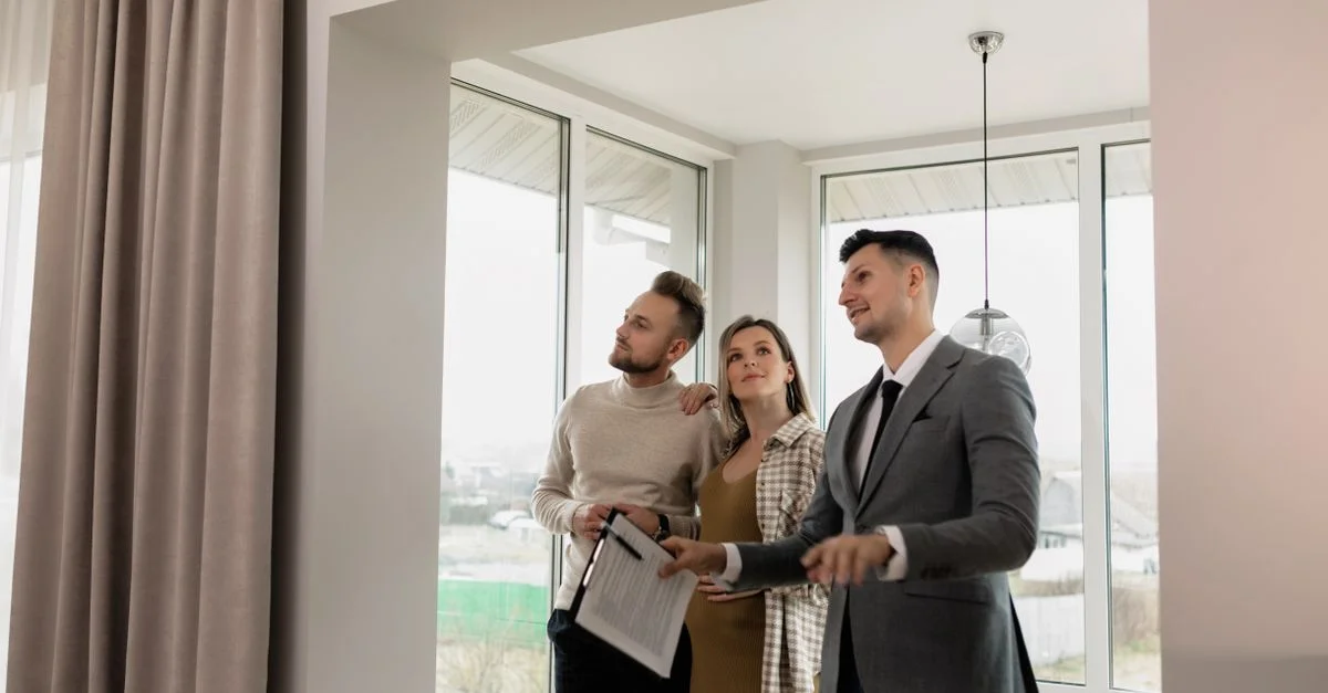 Un agent immobilier montrant une maison moderne à un jeune couple lors d'une visite de jour.