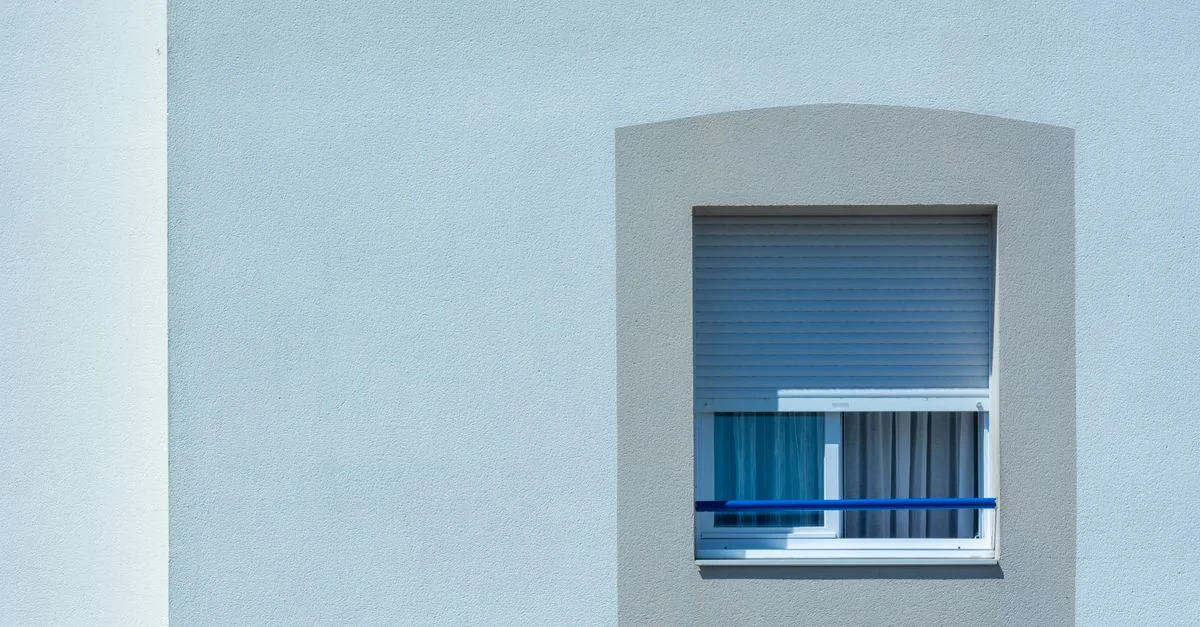 Une fenêtre ensoleillée sur la façade d'un bâtiment urbain minimaliste avec des lignes épurées et une esthétique moderne.