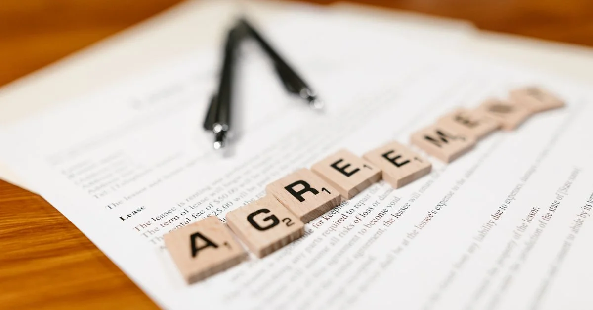 Tuiles de Scrabble épelant 'CONTRAT' sur un document de location, soulignant les thèmes contractuels.