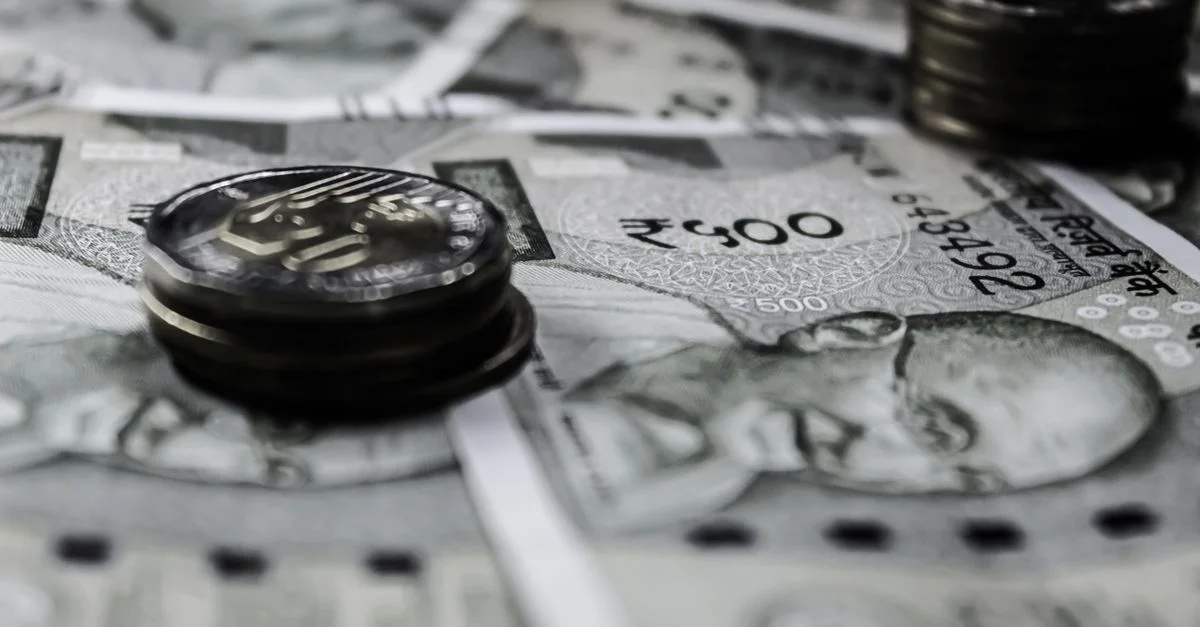 Un gros plan détaillé de billets et de pièces de monnaie indiens, mettant en avant des thèmes financiers.