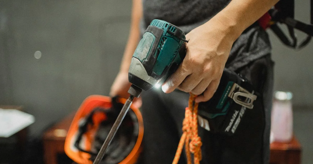 Un travailleur tenant une perceuse et un casque, prêt pour des tâches d'entretien.
