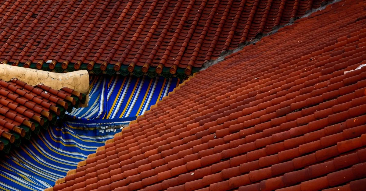 Un gros plan de toits traditionnels en tuiles rouges avec un tissu à motifs vibrants bleu et jaune.