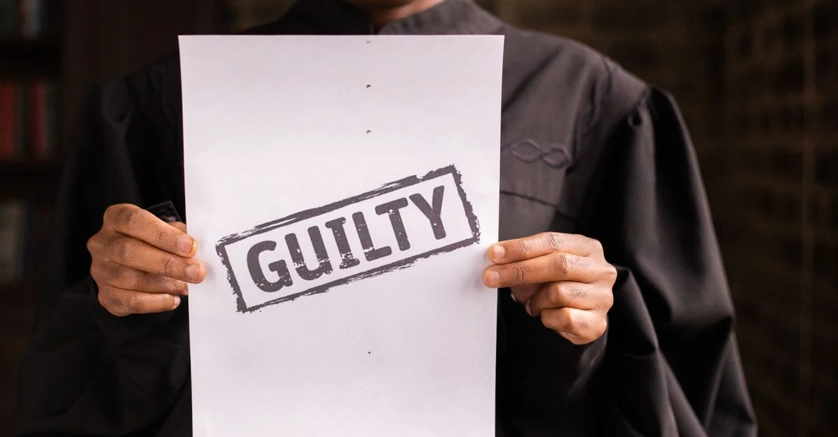 Un juge dans une salle d'audience tenant un document avec un verdict de culpabilité, symbolisant la loi et la justice.