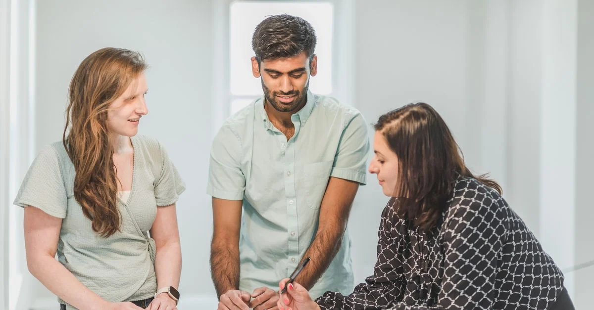 Trois professionnels engagés dans une discussion à l'intérieur, probablement liée à l'immobilier.