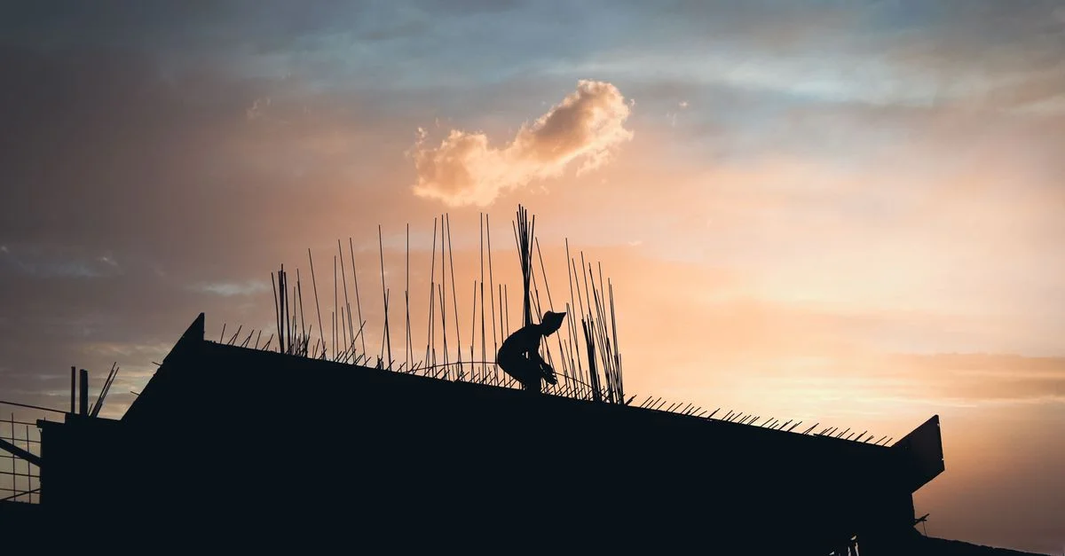 Une silhouette d'un ouvrier du bâtiment travaillant sur un toit pendant un coucher de soleil éclatant.