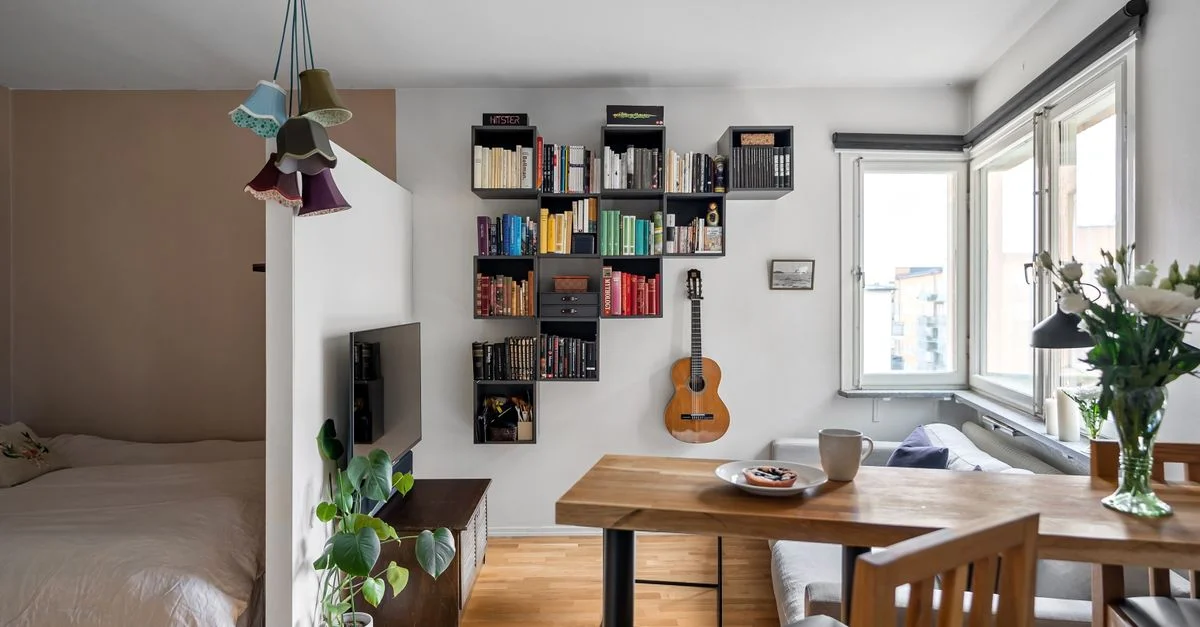 Intérieur d'appartement moderne lumineux et cosy featuring une étagère, une guitare et un coin repas avec lumière naturelle.